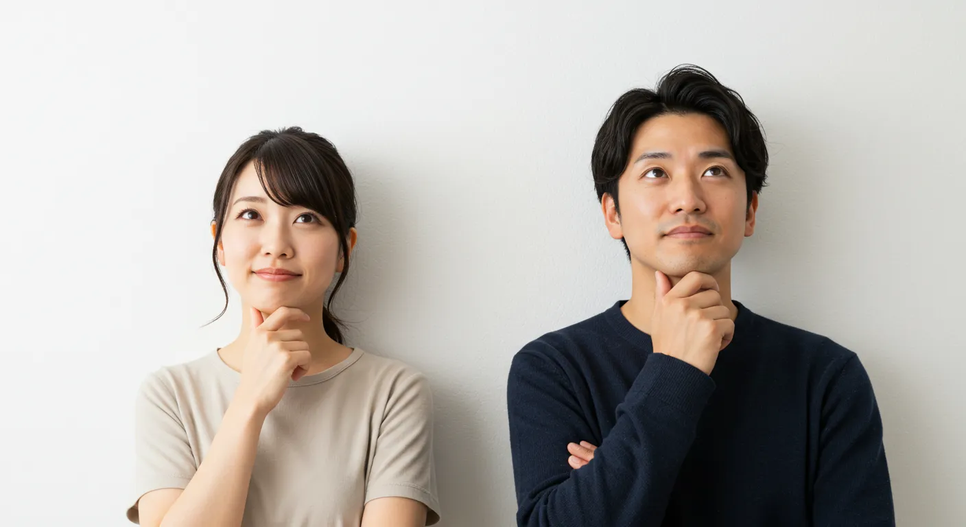 白い壁の前で顎に片手をあてている日本人の男女。視線は少し斜め上をみている
